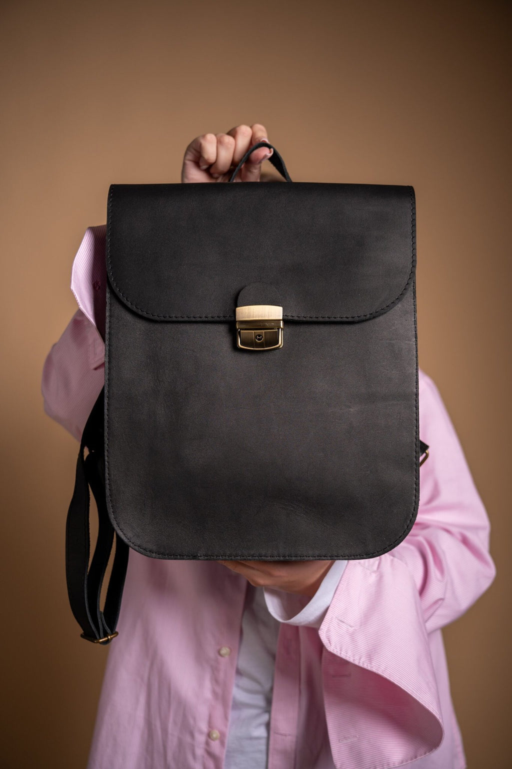 4. Close-up of Zelma Kraft black leather saddle backpack detailing with brass hardware