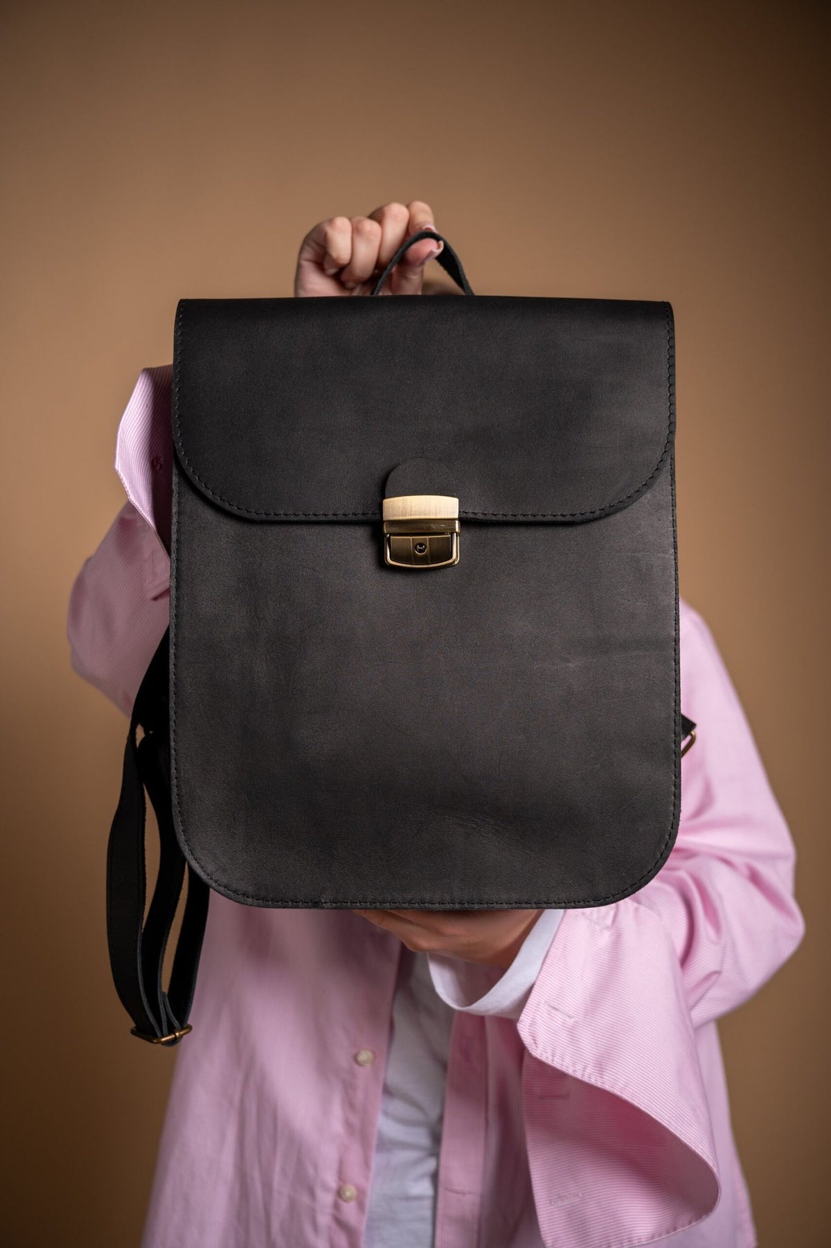 4. Close-up of Zelma Kraft black leather saddle backpack detailing with brass hardware