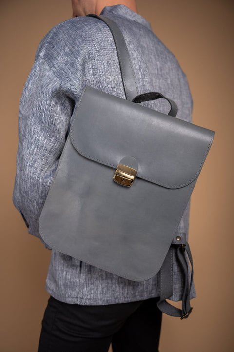5. Close-up of grey Zelma Kraft leather saddle backpack worn by man, highlighting minimalist design