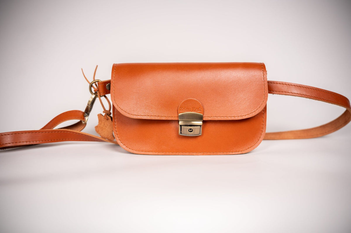 7. Zelma Kraft natural leather saddle bag mini in light brown, shown with adjustable strap and buckle closure