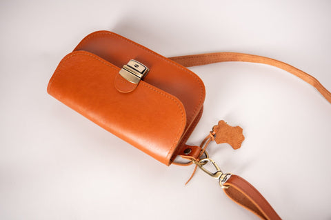 4. Close-up of Zelma Kraft natural leather saddle bag mini in light brown, showing buckle and strap details
