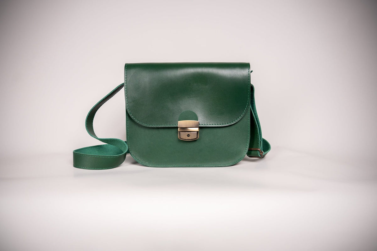 3. Studio shot of Zelma Kraft green leather saddle bag with adjustable strap and buckle closure