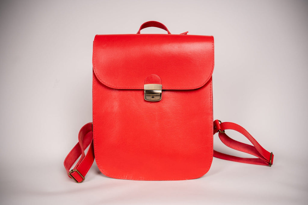 5. Studio shot of Zelma Kraft red leather saddle backpack, featuring semi-glossy finish and metal clasp