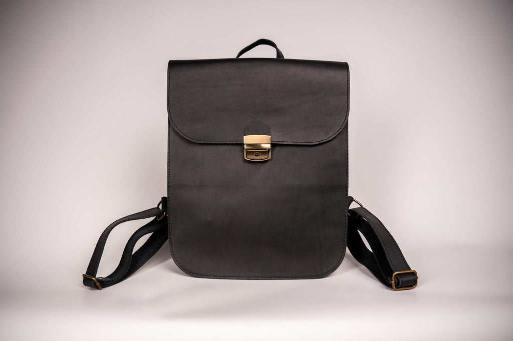 3. Woman holding Zelma Kraft black leather saddle backpack, highlighting minimalist design