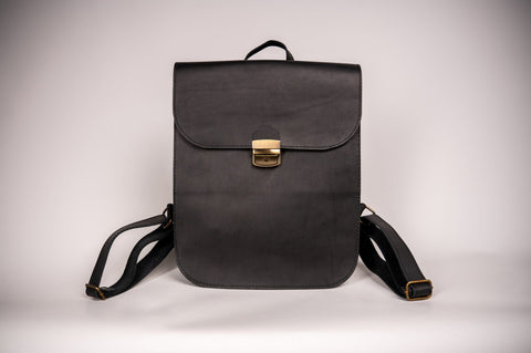 3. Woman holding Zelma Kraft black leather saddle backpack, highlighting minimalist design