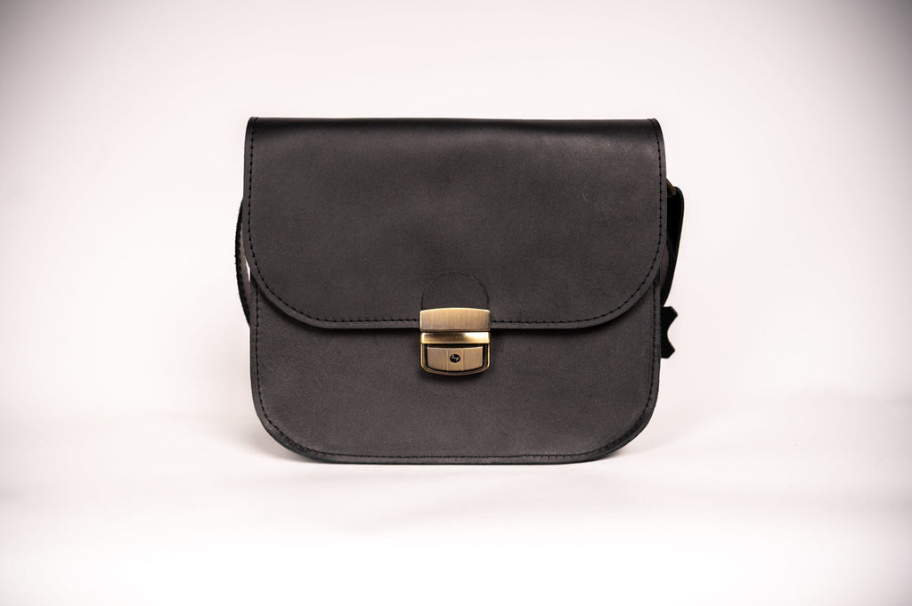 5. Studio shot of Zelma Kraft black leather saddle bag with buckle closure, shown from front