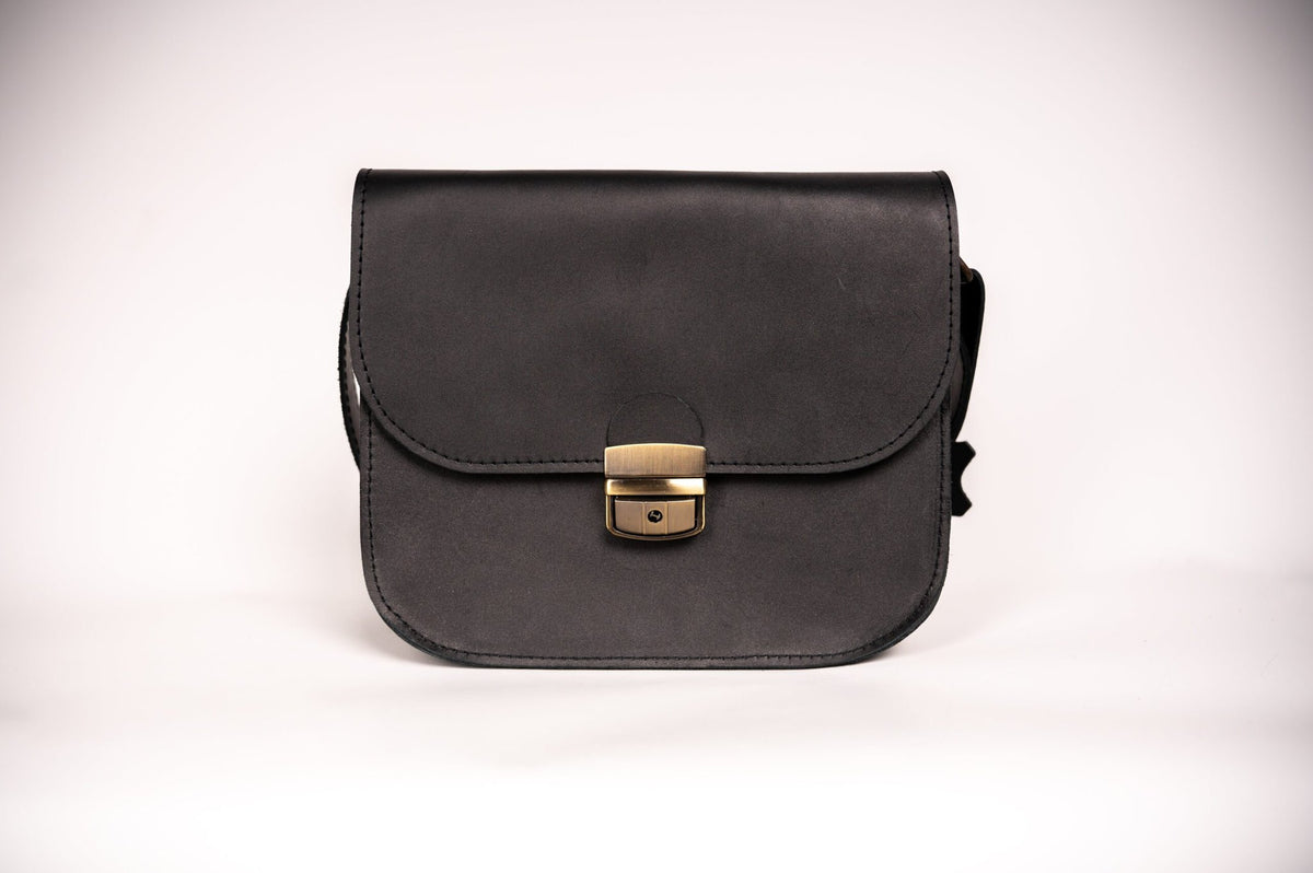 5. Studio shot of Zelma Kraft black leather saddle bag with buckle closure, shown from front