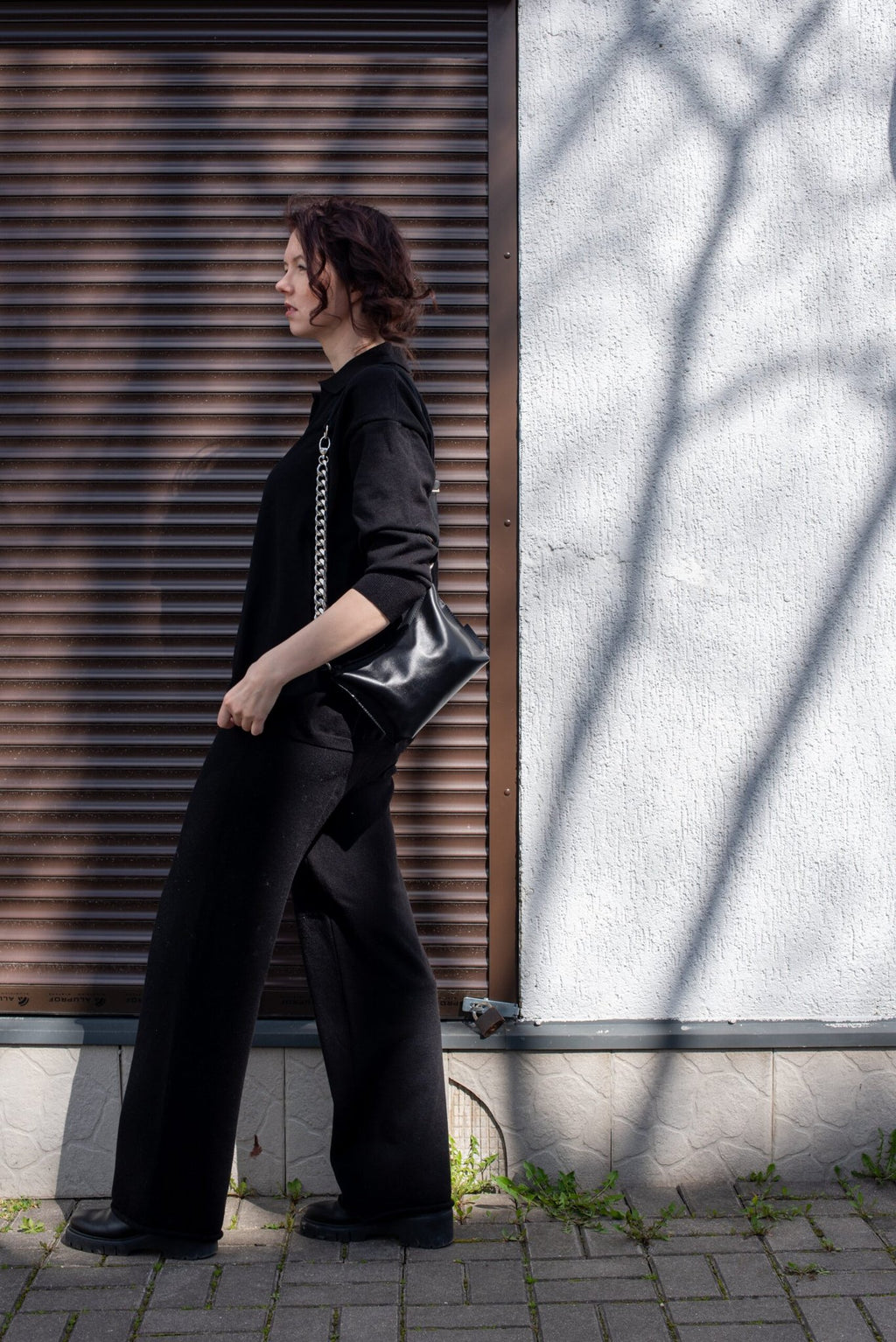 4. Woman walking with Zelma Kraft black leather hobo bag with silver chain in urban setting