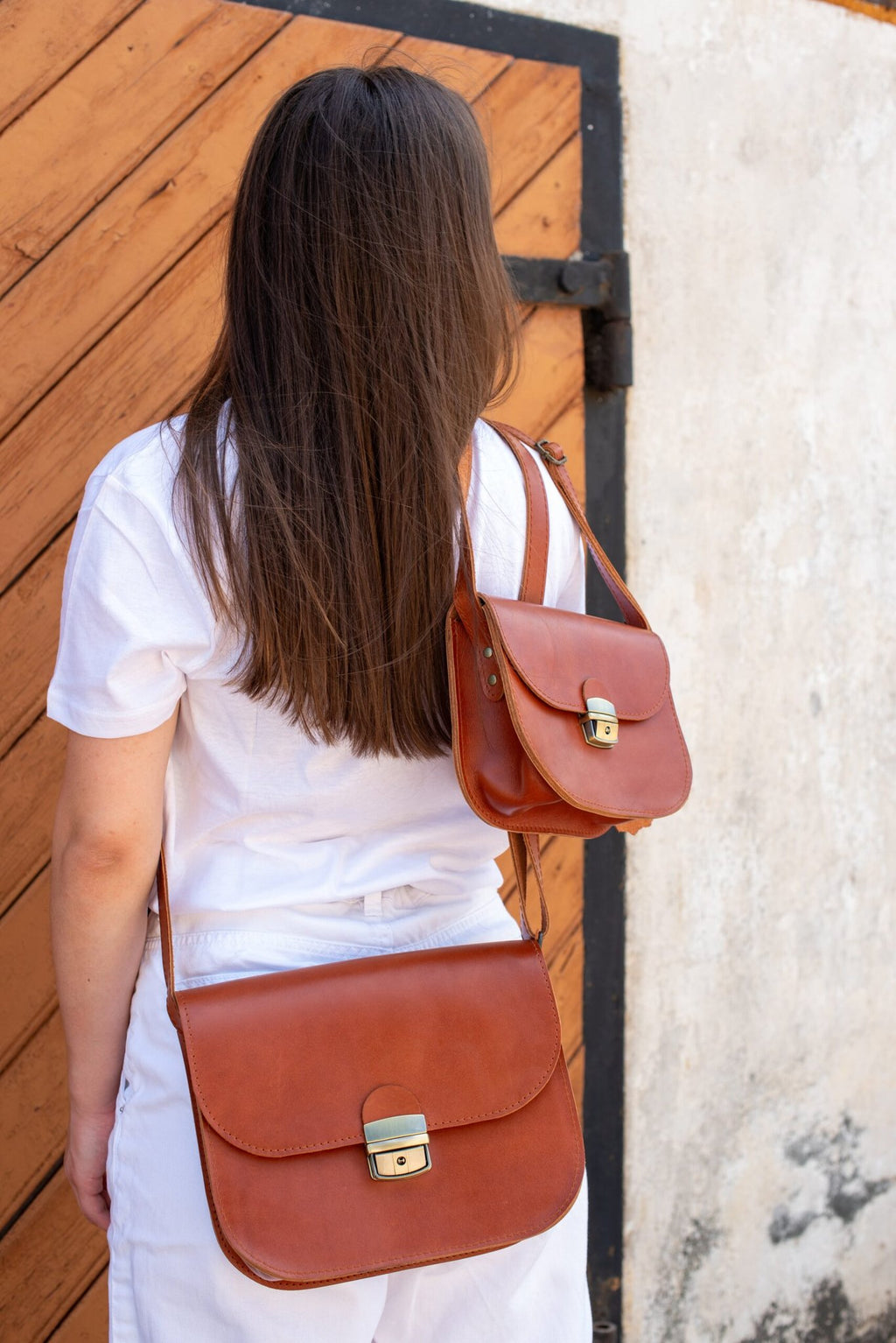 2. Woman wearing two Zelma Kraft natural leather saddle bags in light brown, shown from the back