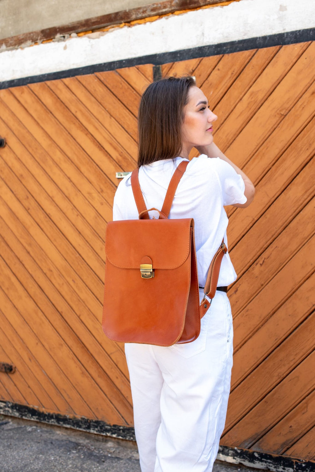 3. Woman wearing Zelma Kraft light brown leather backpack, side view in lifestyle setting