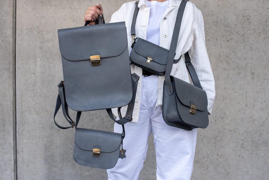 2. Collection of grey Zelma Kraft leather bags including saddle backpack, shown in lifestyle setting
