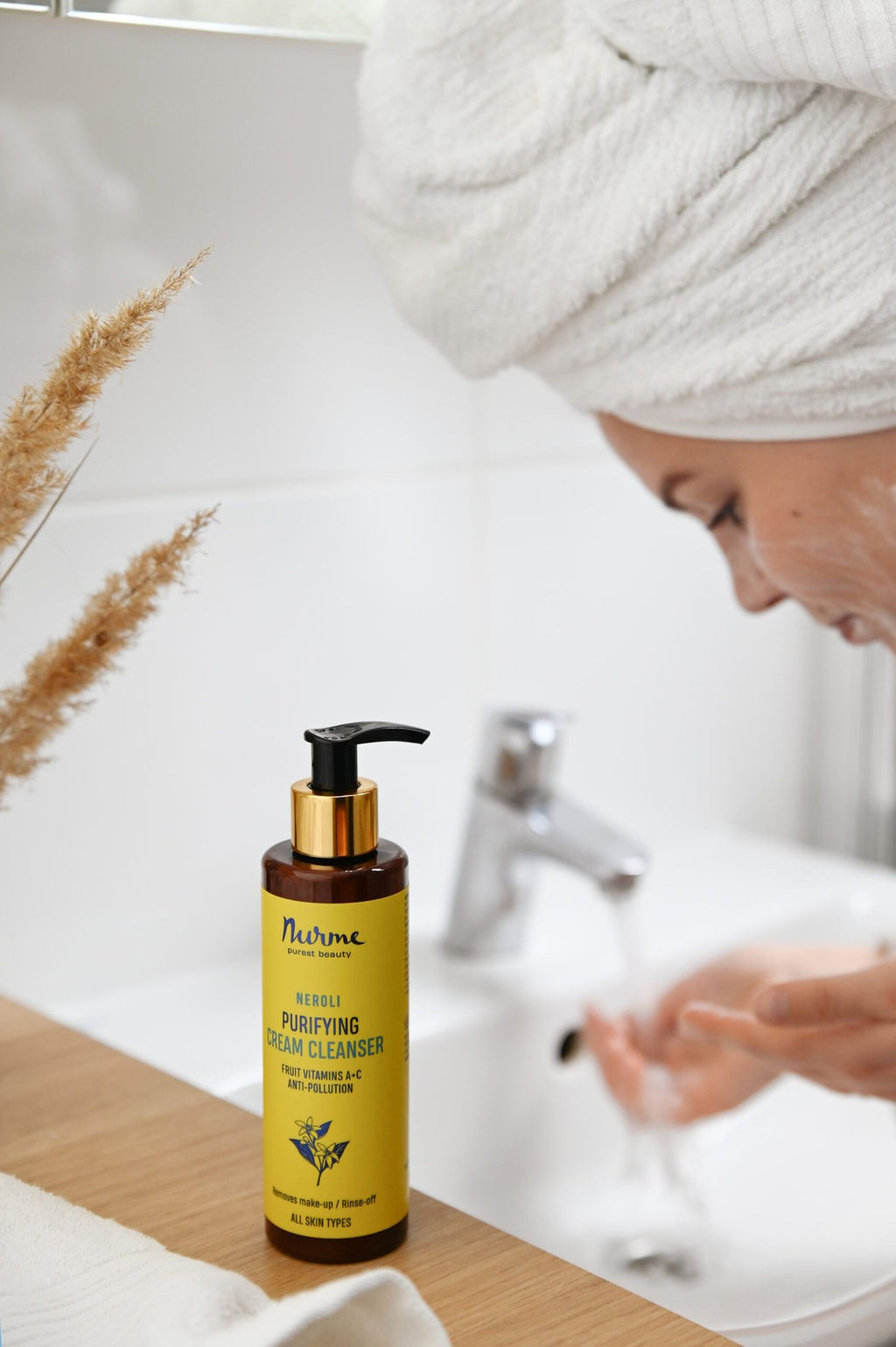 1. Woman using Nurme Neroli purifying cream-foam in bathroom setting