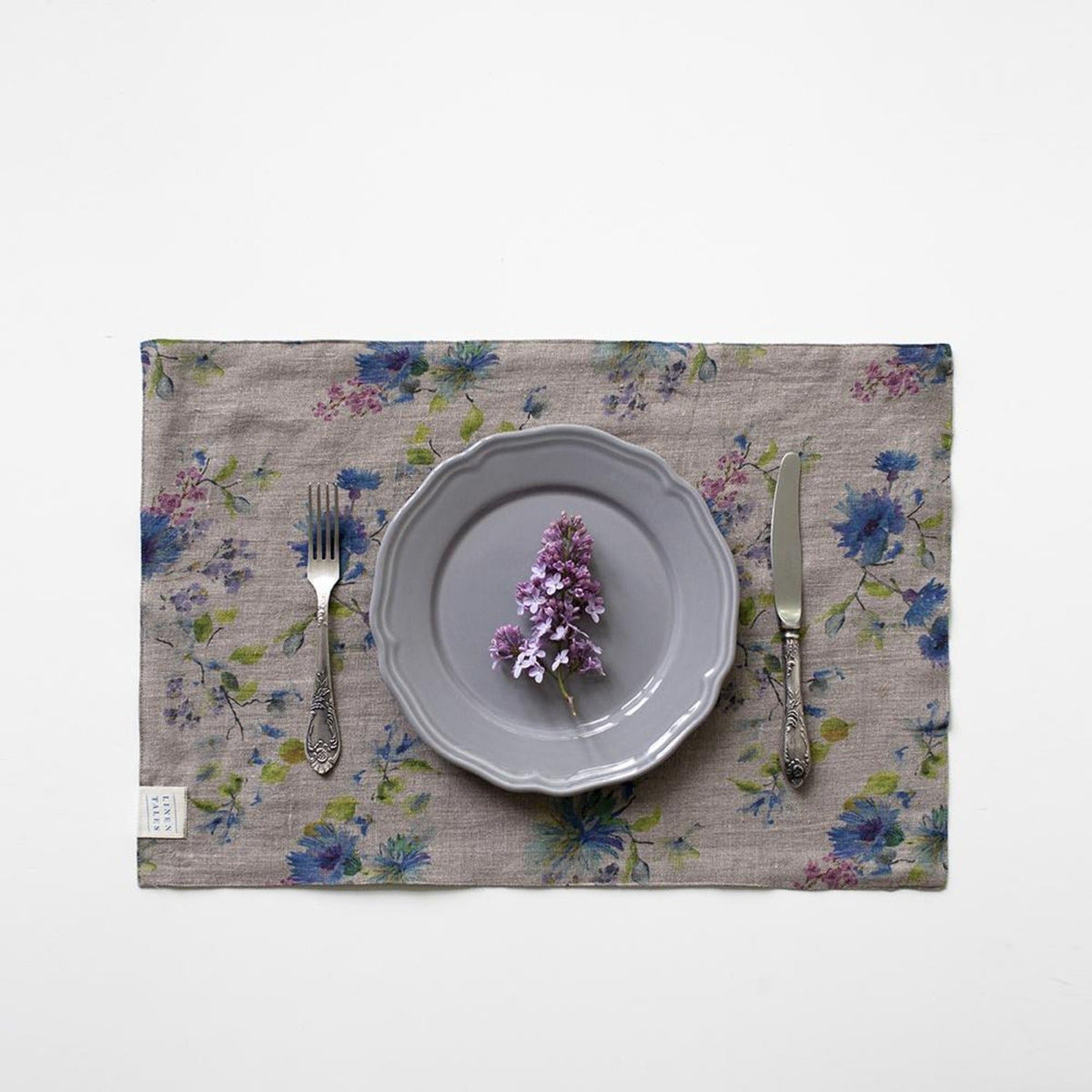 2. Dark floral linen placemat with a purple flower on a grey plate, set with a fork and knife
