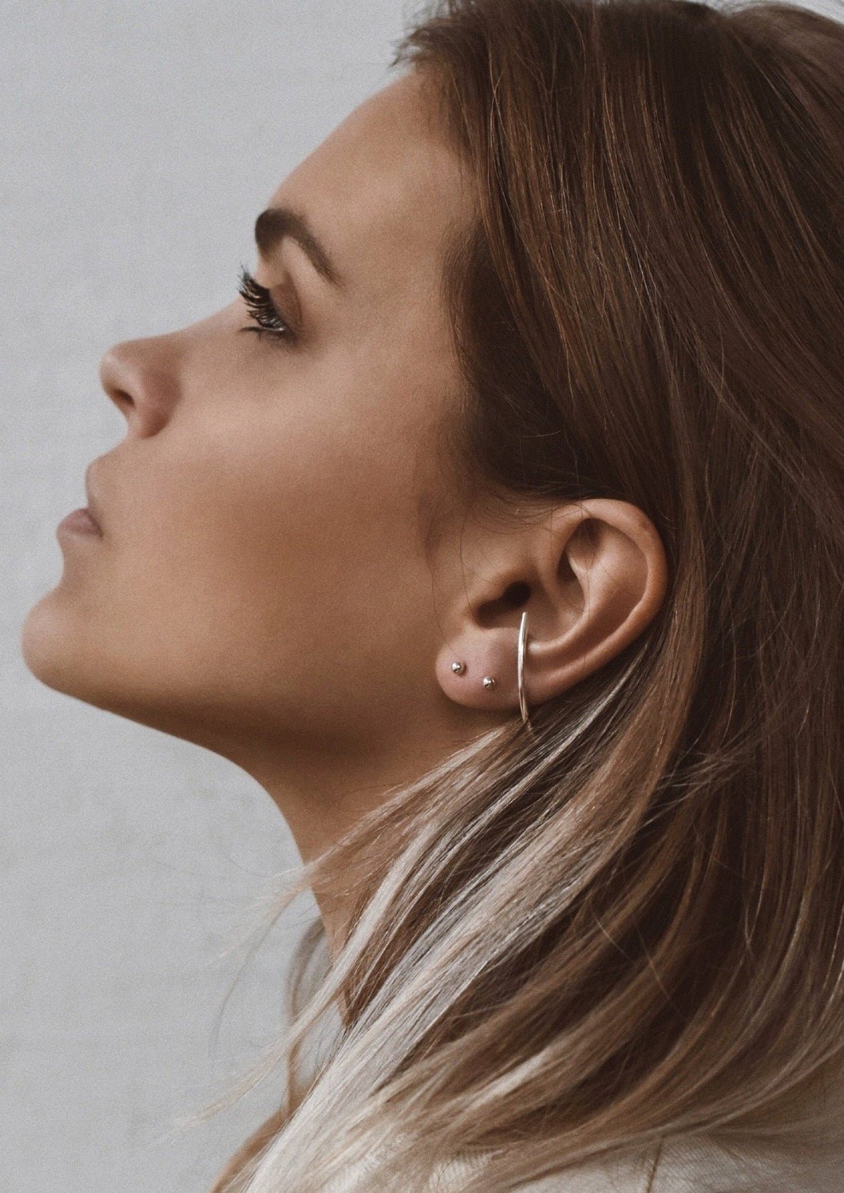 3. Side profile of woman wearing NO MORE Radius earrings in silver, emphasizing sleek design