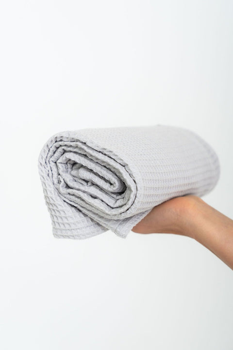 3. Close-up of rolled light gray organic waffle cotton towel held in hand, highlighting texture and craftsmanship