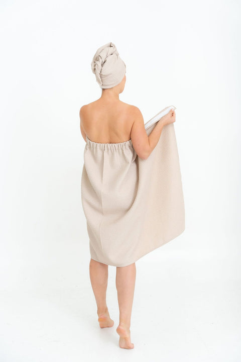 1. Woman in beige spa wrap towel and head wrap, shown from back, highlighting elastic band, on white background