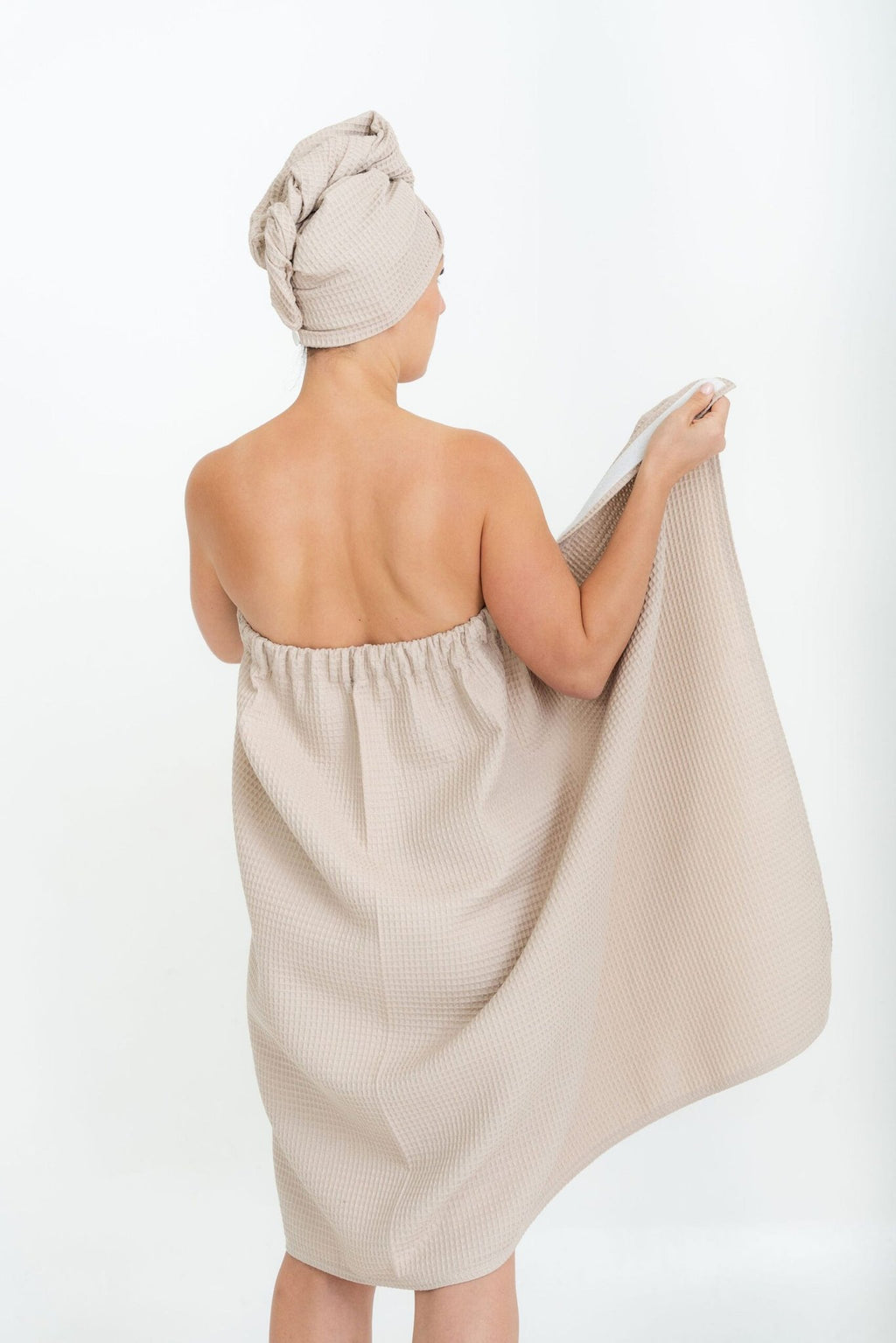 1. Woman wearing beige spa wrap towel with matching head wrap, shown from back, highlighting elastic band, on white background