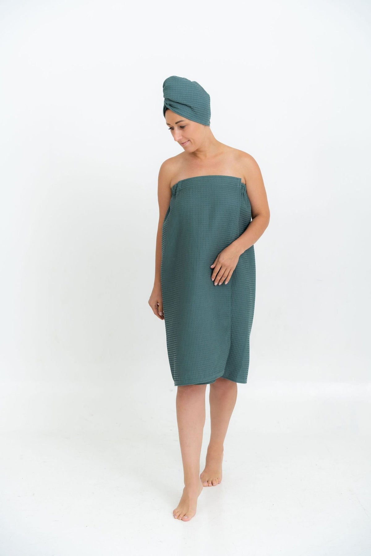 1. Woman in petrol-colored spa wrap towel and head wrap, shown walking, on white background