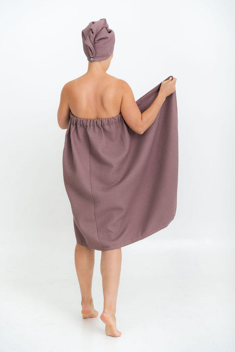 1. Woman in plum-colored spa wrap towel and head wrap, shown from back, highlighting elastic band, on white background