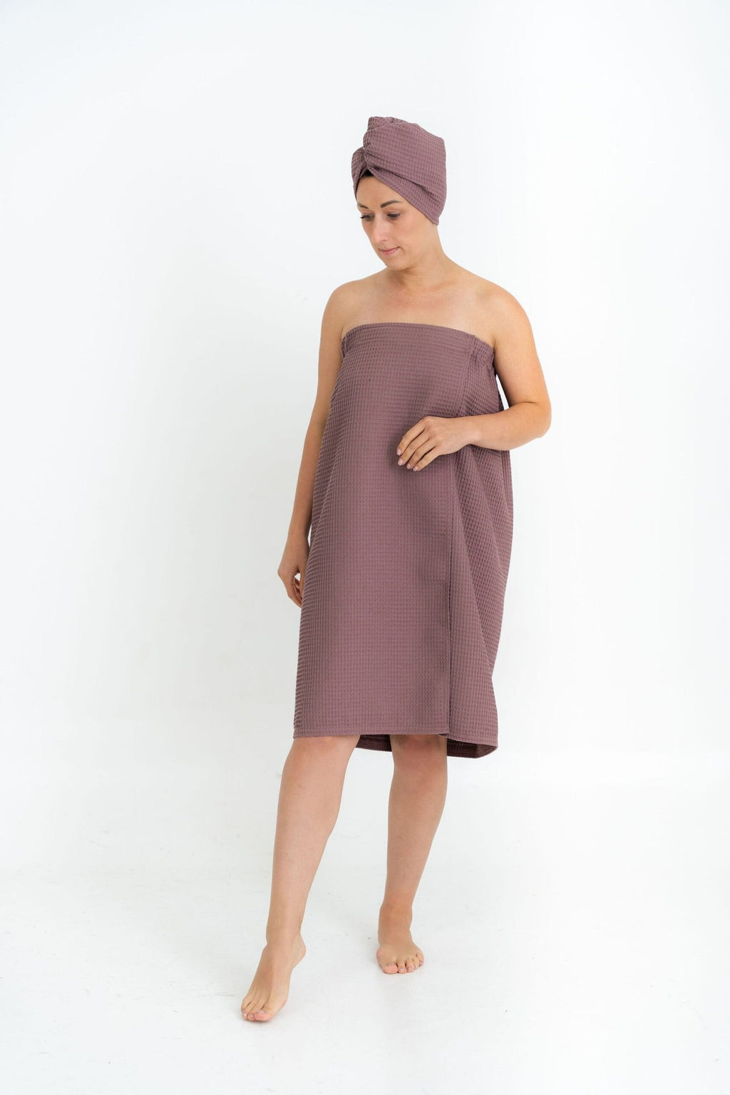 1. Woman in plum-colored spa wrap towel and head wrap, shown walking, on white background