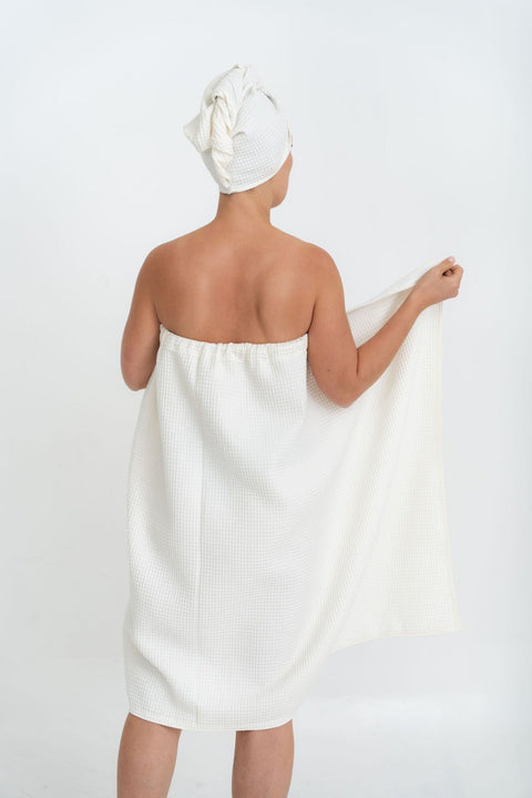 1. Woman in white spa wrap towel and head wrap, shown from back, highlighting elastic band, on white background