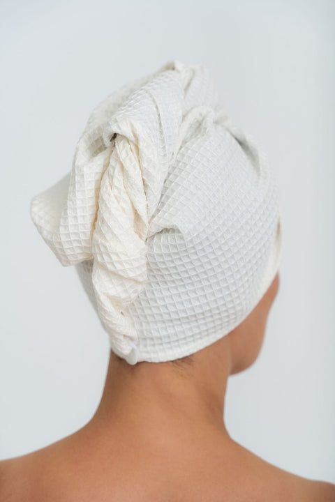 2. Back view of woman wearing cream cotton hair towel with button closure, highlighting texture