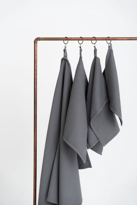 4. Four gray waffle cotton towels hanging on a copper rack in a studio setting