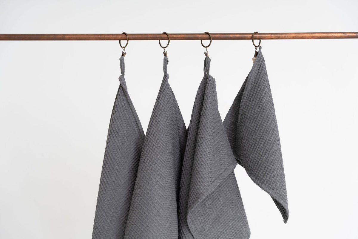 3. Close-up of four gray waffle cotton towels hanging from copper hooks
