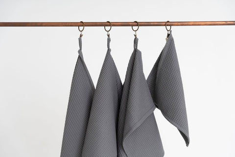 3. Close-up of four gray waffle cotton towels hanging from copper hooks