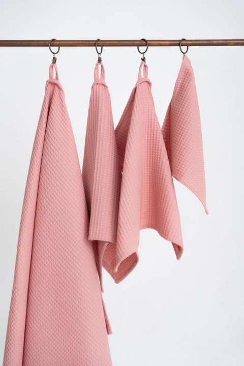 4. Four peach waffle cotton towels hanging on a rod, displaying various sizes and texture