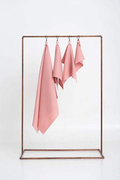 1. Set of four peach waffle cotton towels hanging on a metal rack, showcasing different sizes for versatile use
