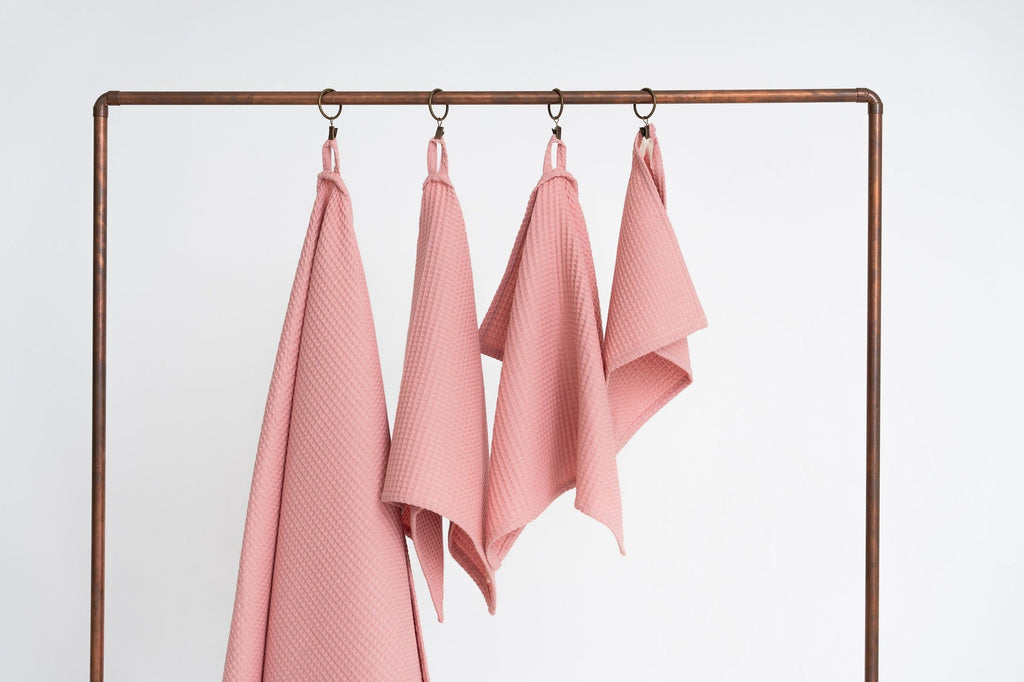 5. Peach waffle cotton towels in four sizes hanging on a metal rack, emphasizing texture and design