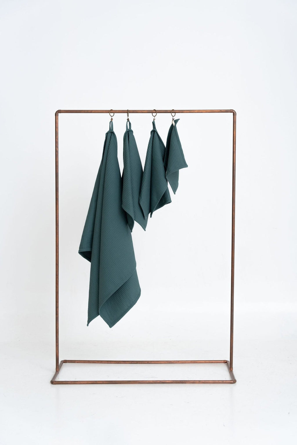 5. Size chart for petrol organic waffle cotton towels showing four sizes hanging on a copper rack