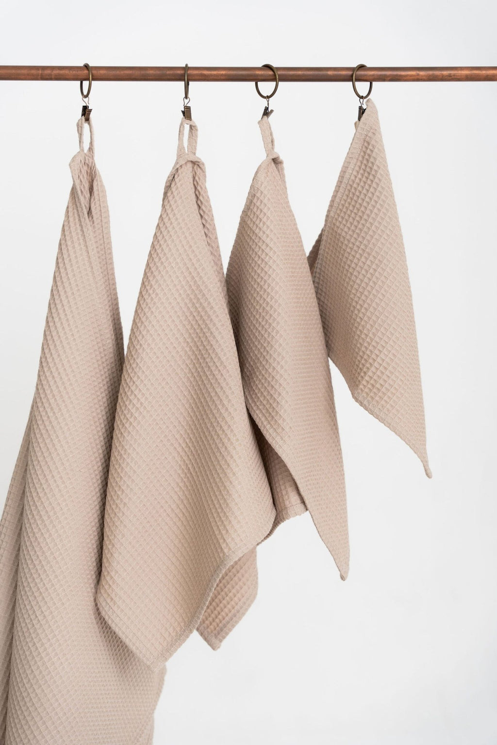 4. Detail of beige waffle cotton towels hanging from hooks, emphasizing texture and craftsmanship
