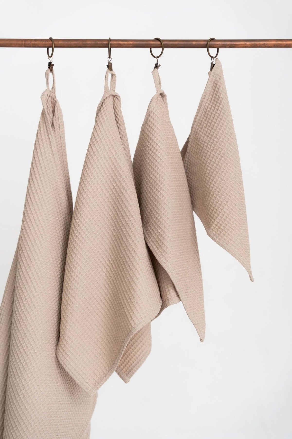 4. Detail of beige waffle cotton towels hanging from hooks, emphasizing texture and craftsmanship