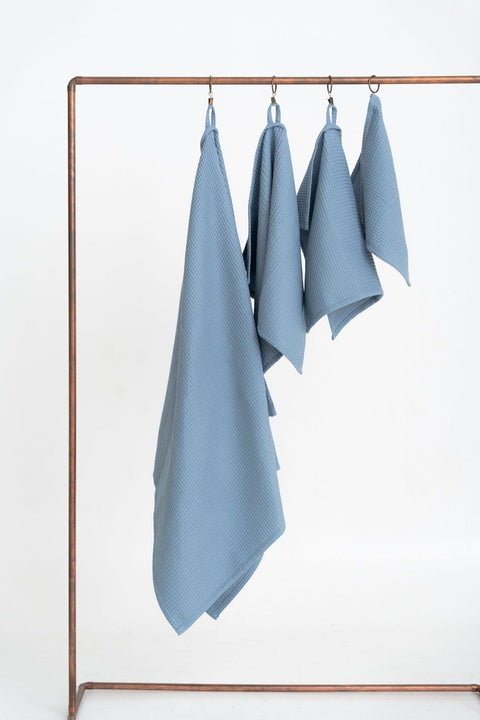 3. Full view of blue waffle cotton towels set on copper rod, displaying various sizes and hanging loops