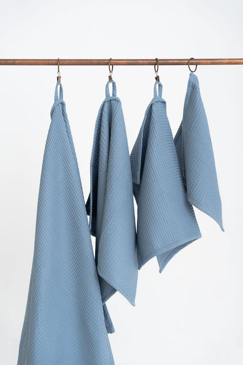 2. Blue waffle cotton towels in four sizes hanging on copper rod, highlighting texture and hanging loops