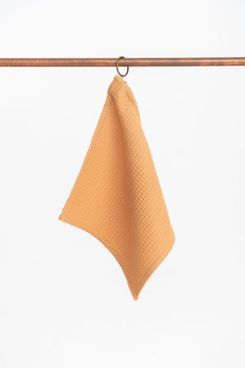 4. Single caramel waffle cotton towel with hanging loop on a metal rod, displayed against a white background