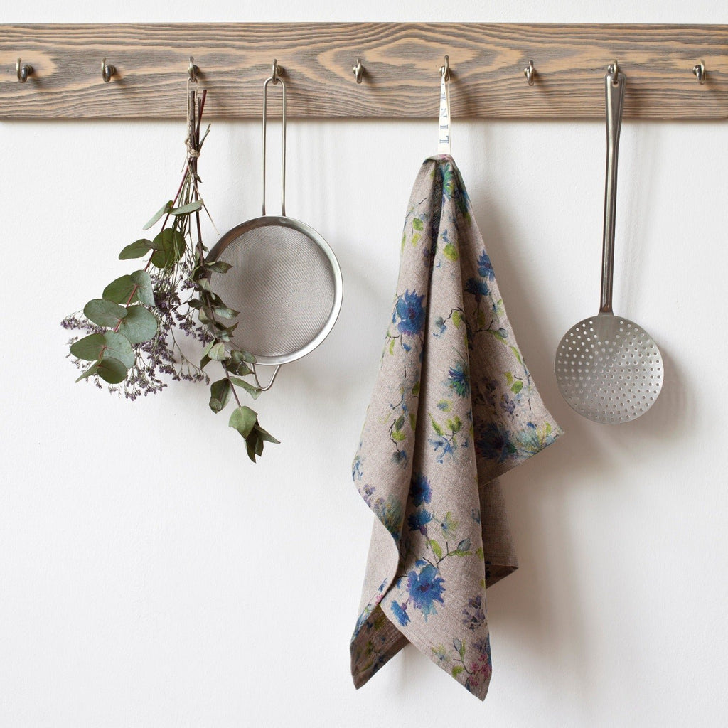 7. Floral print linen kitchen towel hanging on wooden rack with kitchen utensils and dried flowers