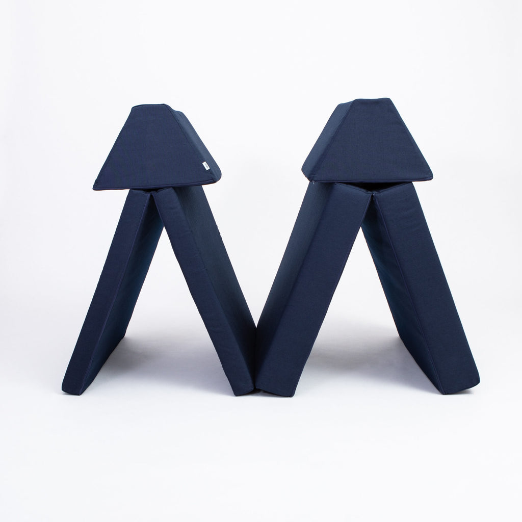 2. Navy blue play mattress set configured as two tents with trapezoidal pillows on a white background