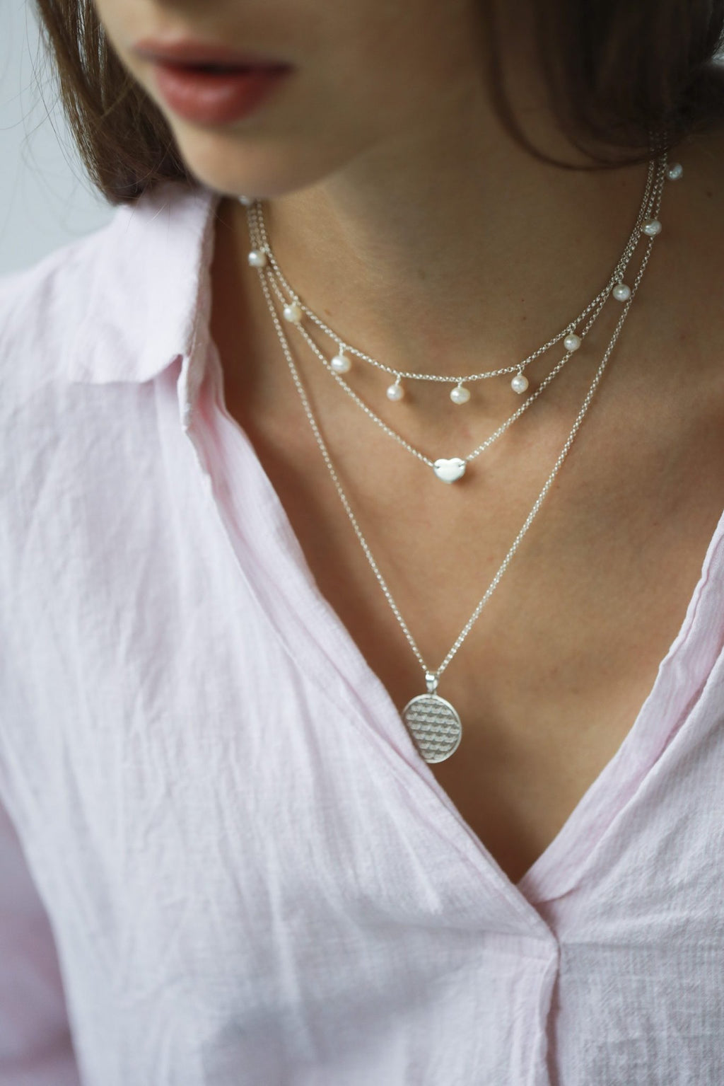 2. Woman wearing layered necklaces including New Vintage by Kriss Flower Of Life necklace in silver