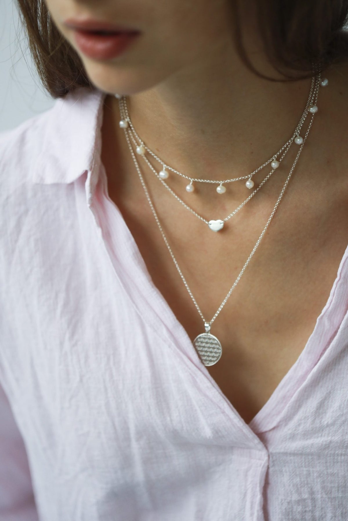 2. Woman wearing layered necklaces including New Vintage by Kriss Flower Of Life necklace in silver