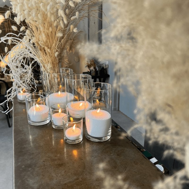 1. Lifestyle image of Candledust powdered candles in glass containers, creating a cozy atmosphere with warm lighting on a decorated table