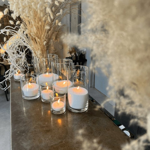 1. Lifestyle image of Candledust powdered candles in glass containers, creating a cozy atmosphere with warm lighting on a decorated table