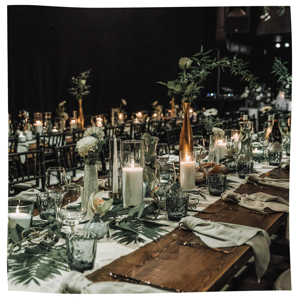 2. Elegant table setting with Candledust powdered candles in tall glass holders, enhancing a sophisticated dining ambiance
