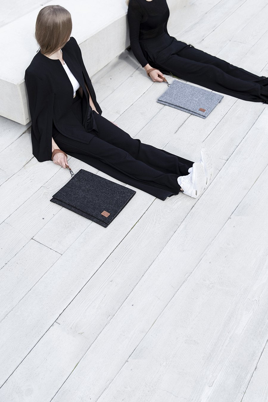 1. Women's Nordhale Berg black laptop bag in lifestyle setting, shown with models sitting on wooden floor