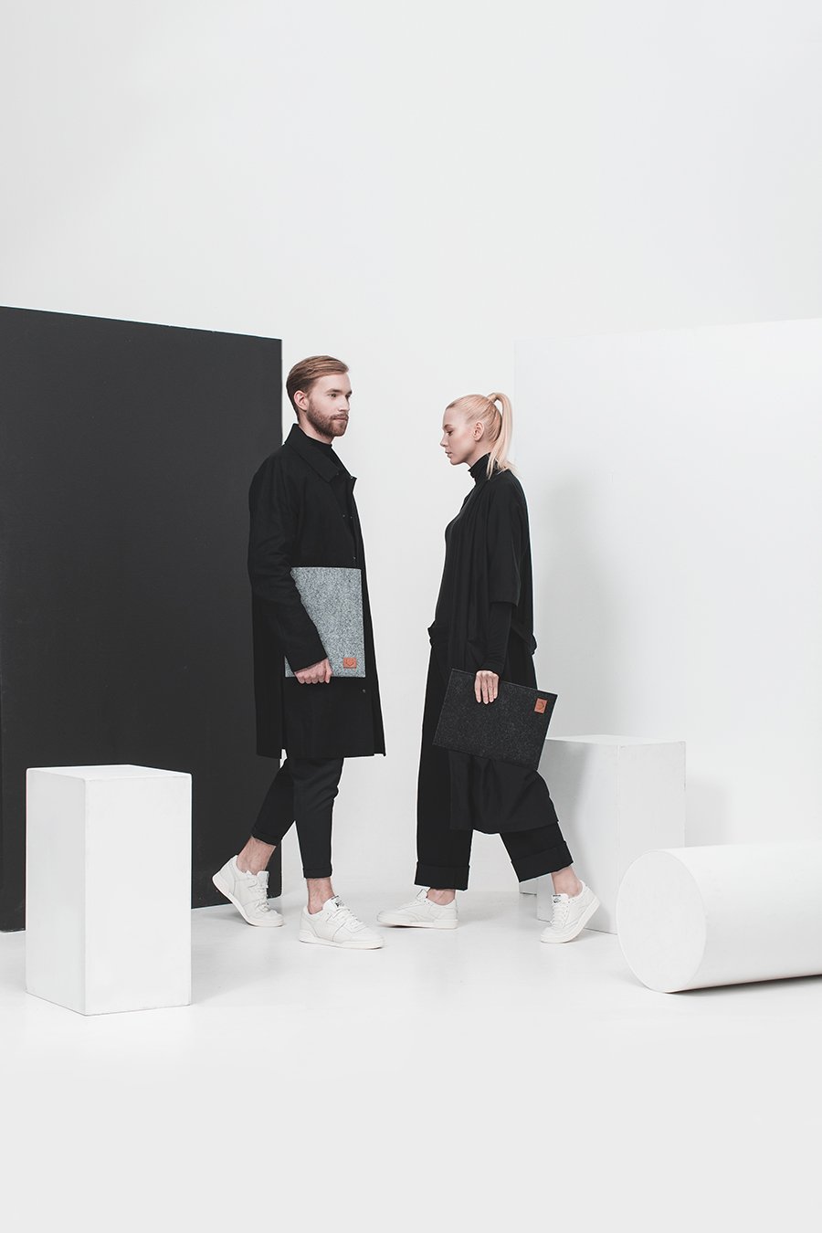 1. Unisex models holding Nordhale Bodem 15' black laptop sleeve in a minimalist studio setting