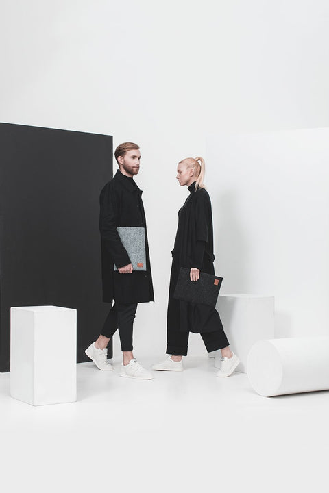 1. Unisex models holding Nordhale Bodem 15' black laptop sleeve in a minimalist studio setting