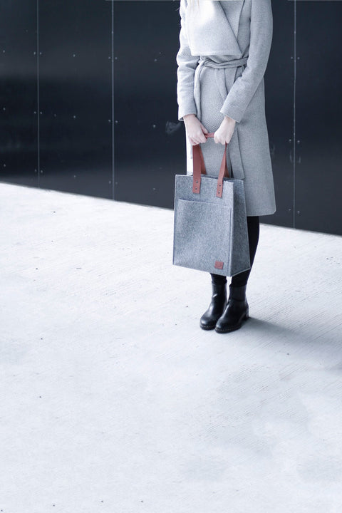 1. Woman in grey coat holding Nordhale Hennes Tote Bag in grey, showcasing minimalist style in lifestyle setting