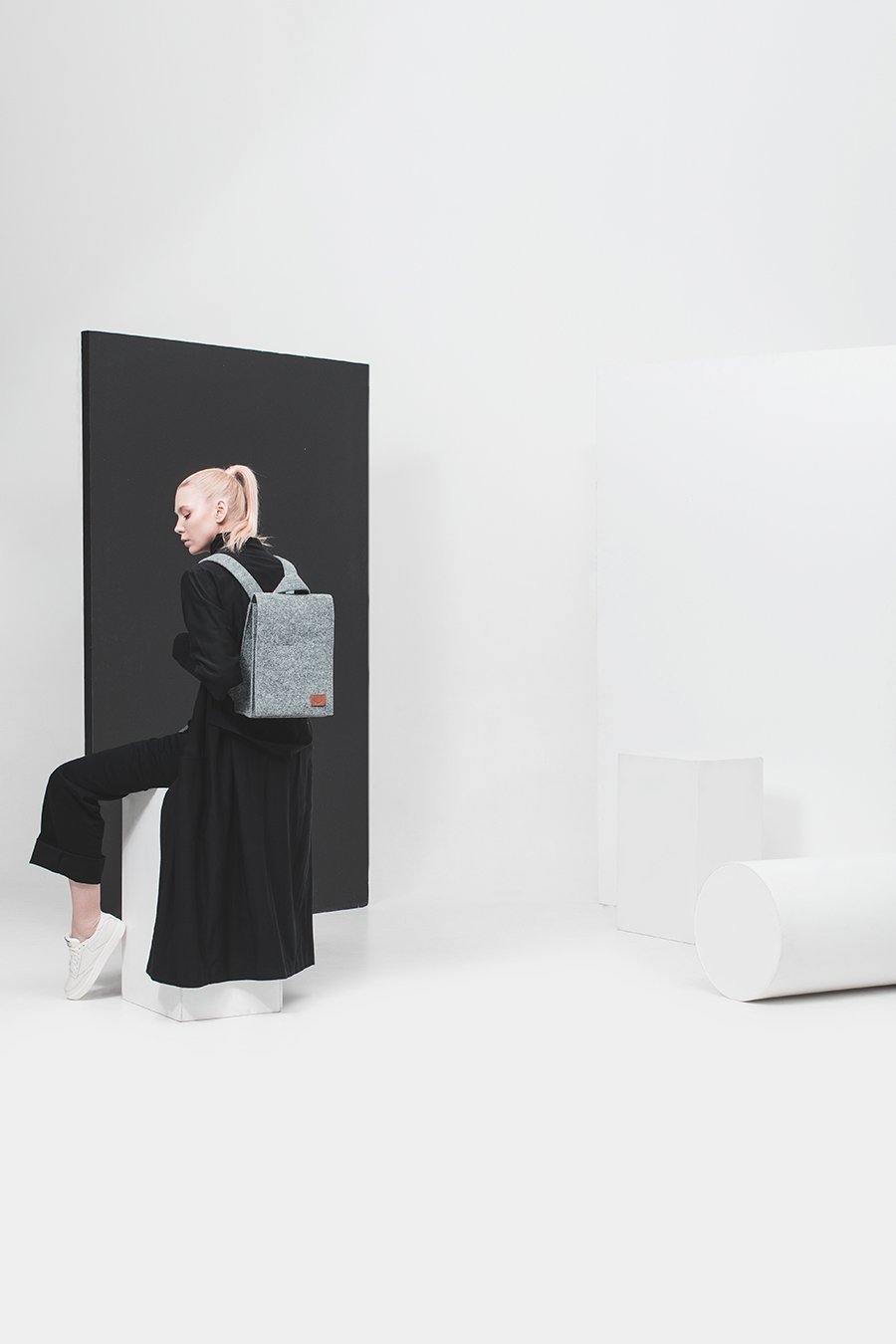 1. Woman wearing Nordhale Lund Mini Backpack in grey, styled in a minimalist studio setting
